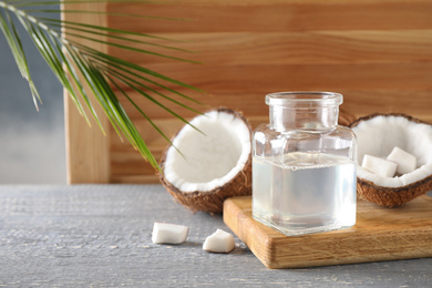 Photo of Coconut oil on grey wooden table, space for text