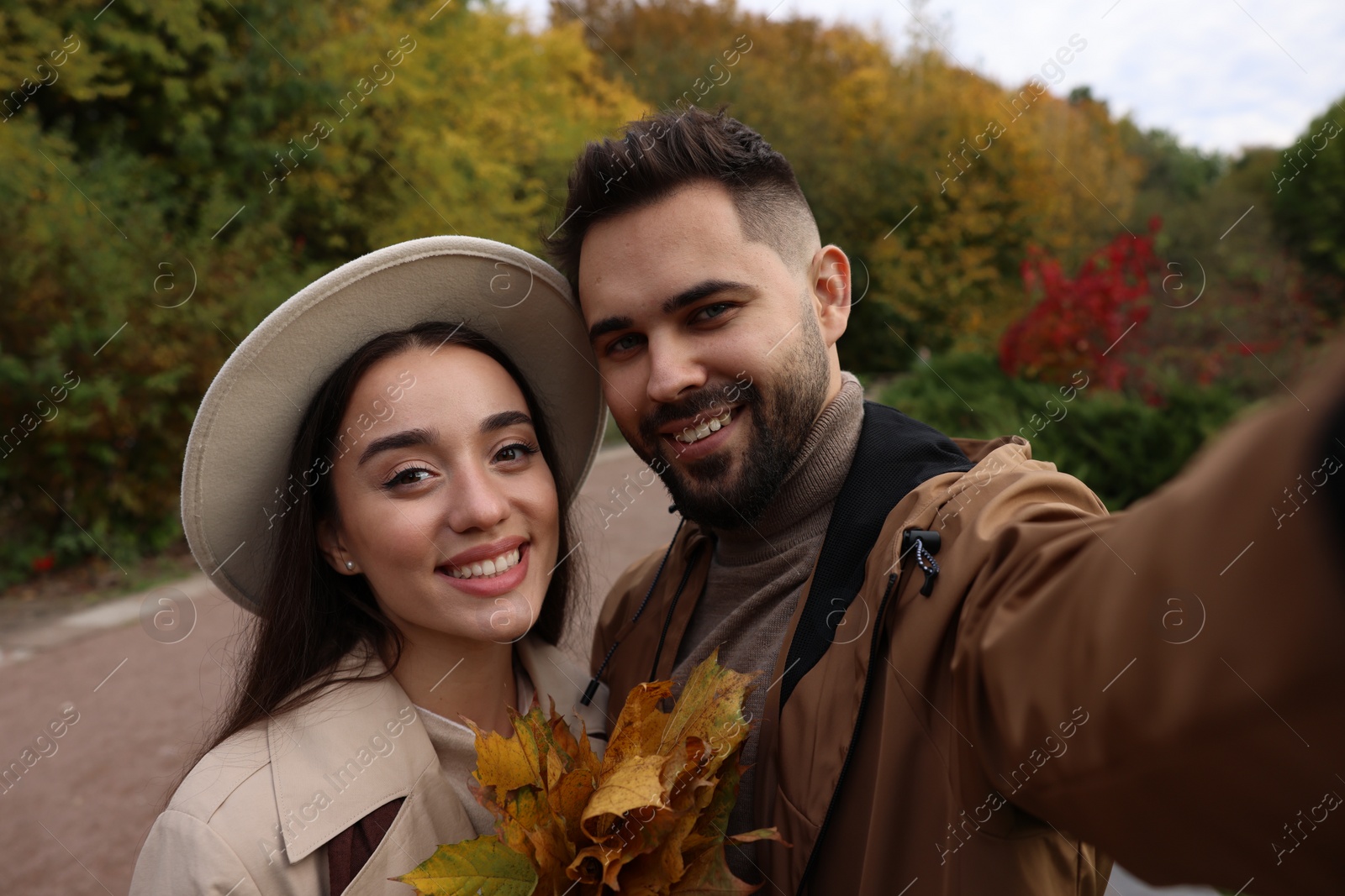 Photo of Happy young couple taking selfie in autumn park