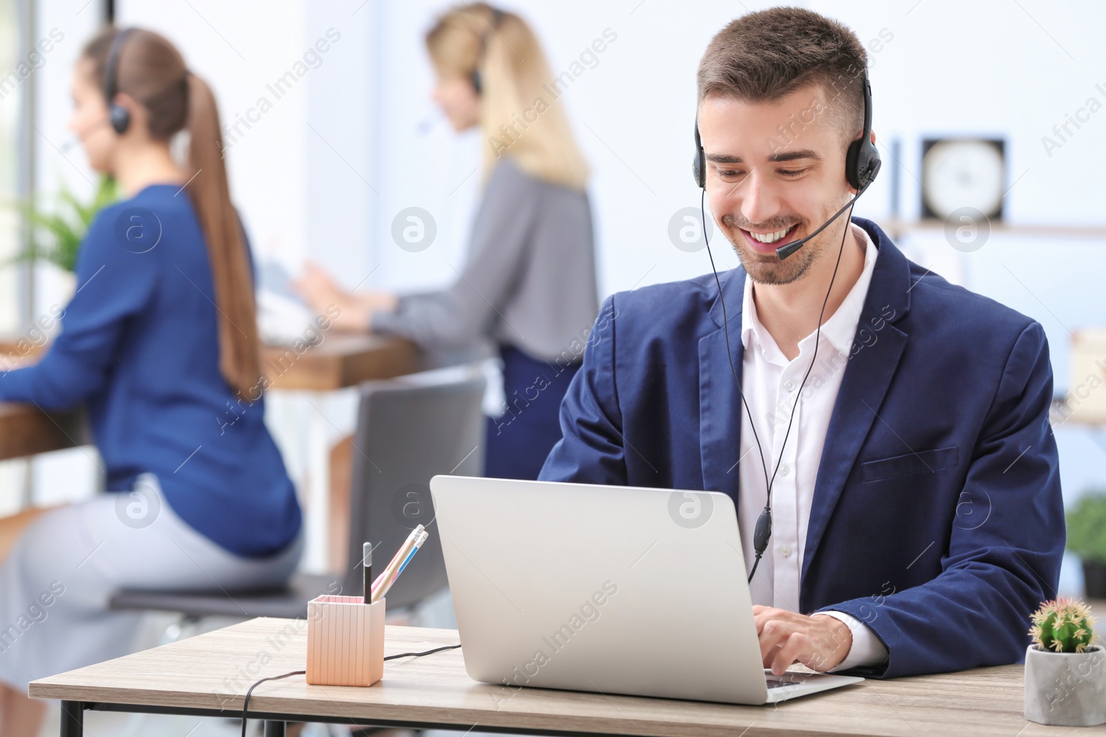 Photo of Male receptionist with headset at desk in office