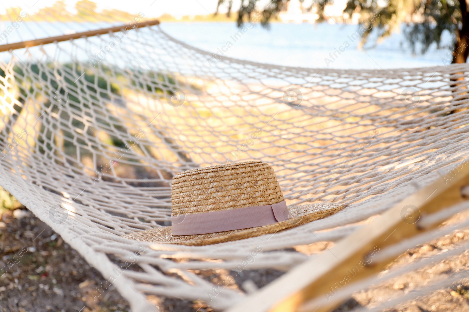 Photo of Hat in comfortable hammock on beach, closeup. Summer vacation