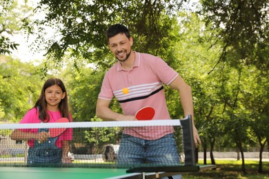Photo of Happy man with his daughter playing ping pong in park