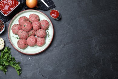 Photo of Many fresh raw meatballs and ingredients on black table, flat lay. Space for text