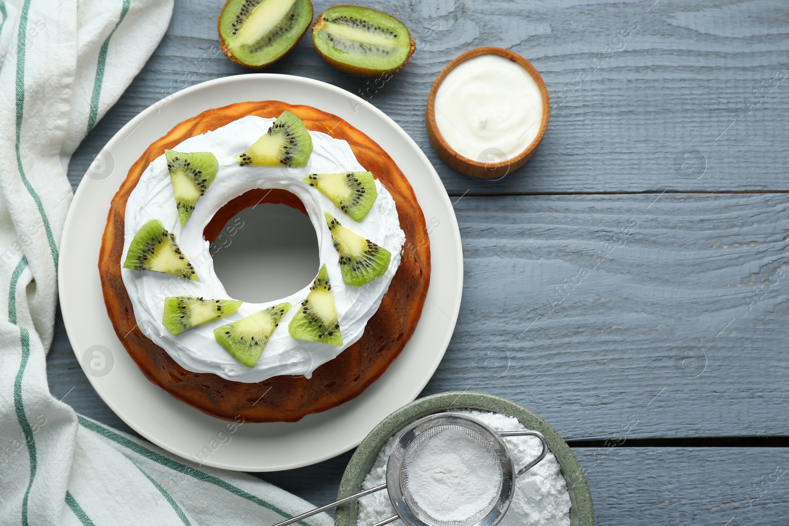 Photo of Homemade yogurt cake with kiwi and cream on grey wooden table, flat lay. Space for text