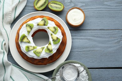 Photo of Homemade yogurt cake with kiwi and cream on grey wooden table, flat lay. Space for text