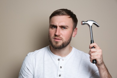 Photo of Young working man with hammer on beige background