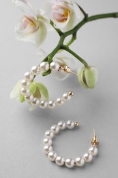Photo of Elegant pearl earrings and orchid flowers on white background, closeup