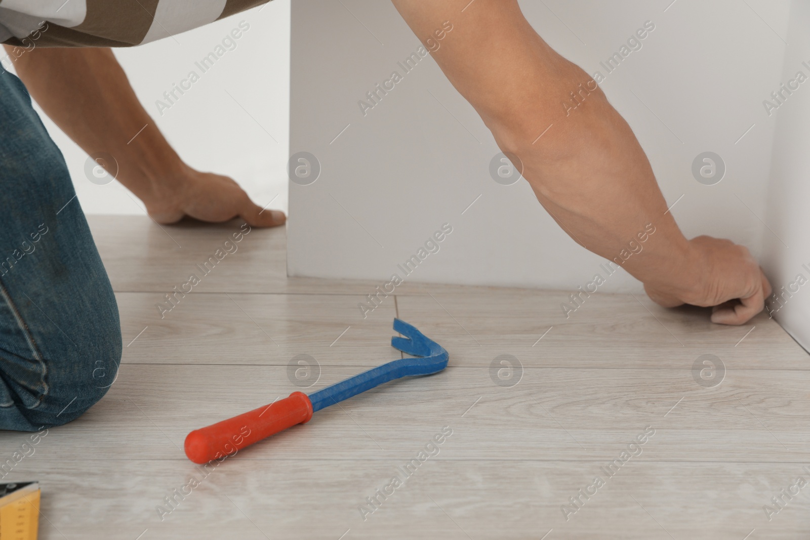 Photo of Professional worker installing new laminate flooring indoors, closeup