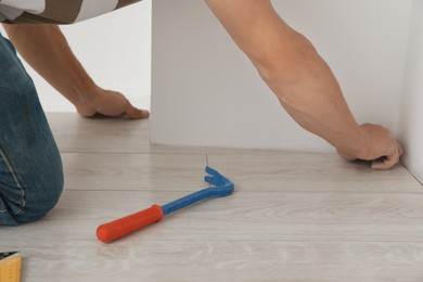 Photo of Professional worker installing new laminate flooring indoors, closeup
