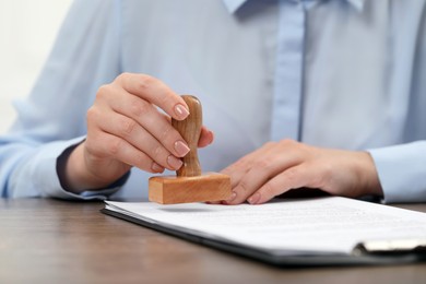 Woman stamping document at wooden table, closeup