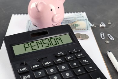 Image of Calculator with word Pension, piggy bank, money and stationery on grey table, closeup