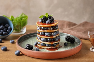 Photo of Tasty pancakes with berries and syrup on plate