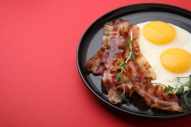 Photo of Fried eggs, bacon and microgreens on red background, space for text