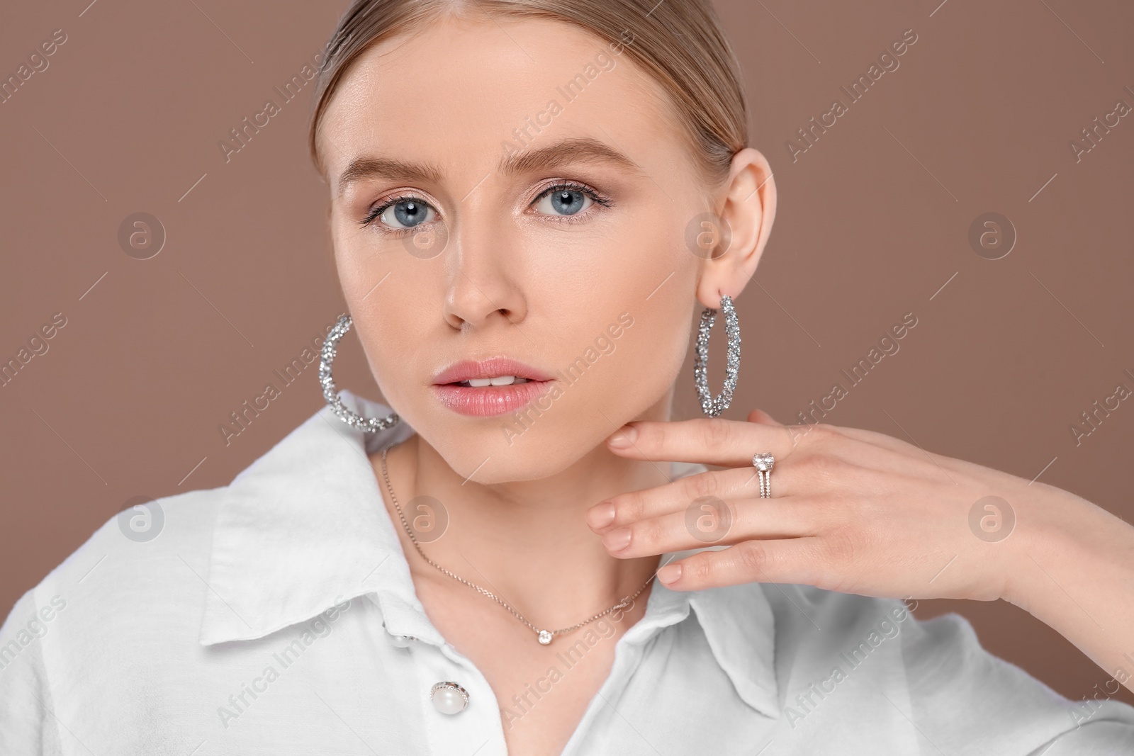 Photo of Beautiful young woman with elegant jewelry on light brown background