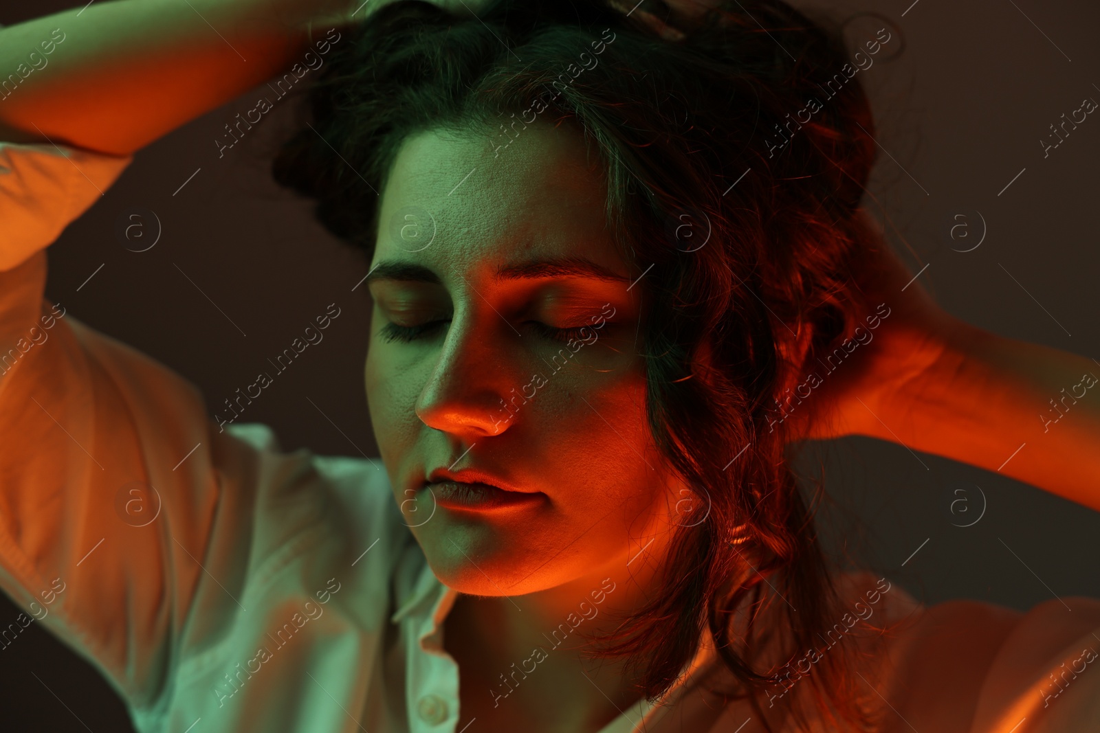 Photo of Portrait of beautiful young woman on color background with neon lights, closeup