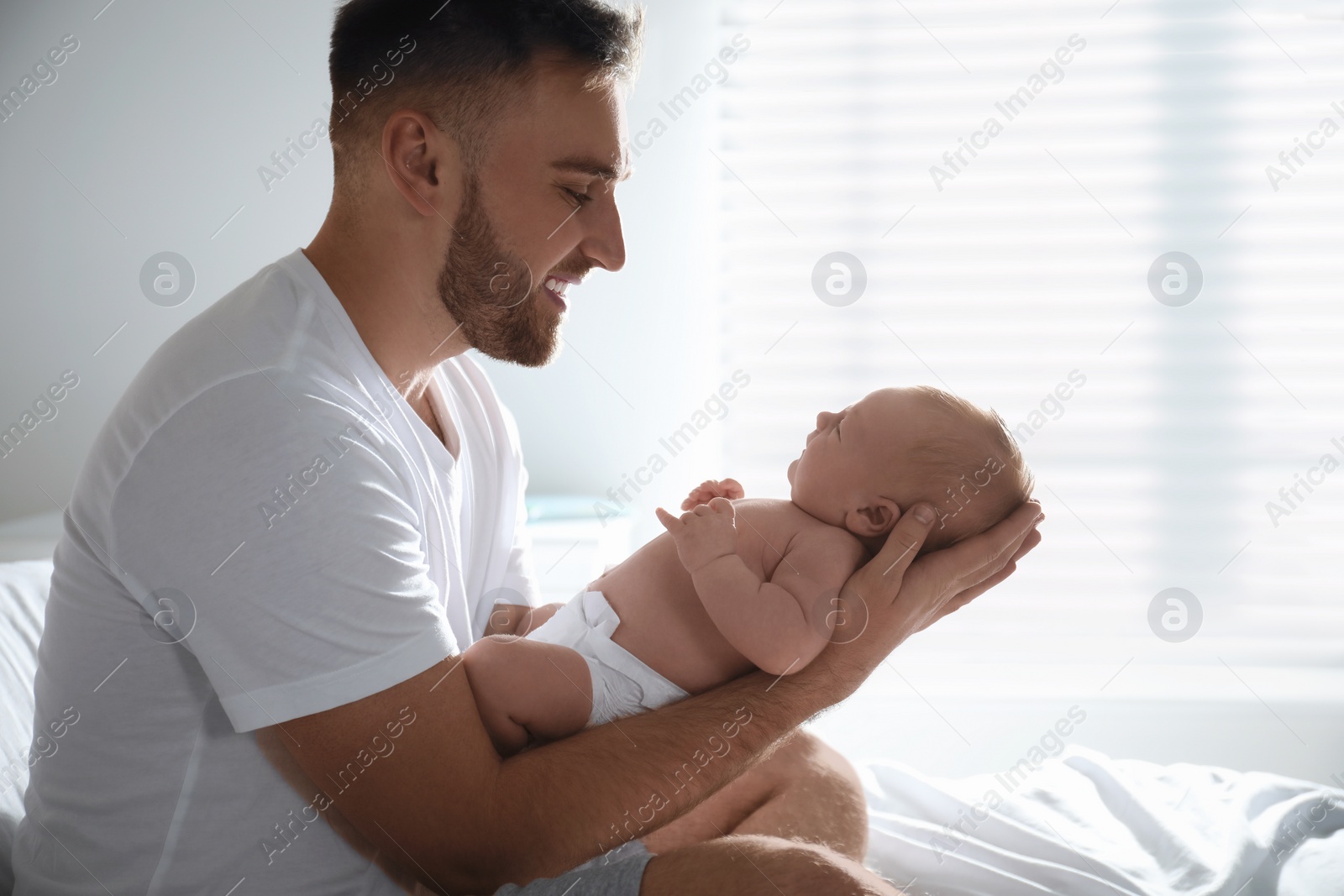 Photo of Father with his newborn son at home