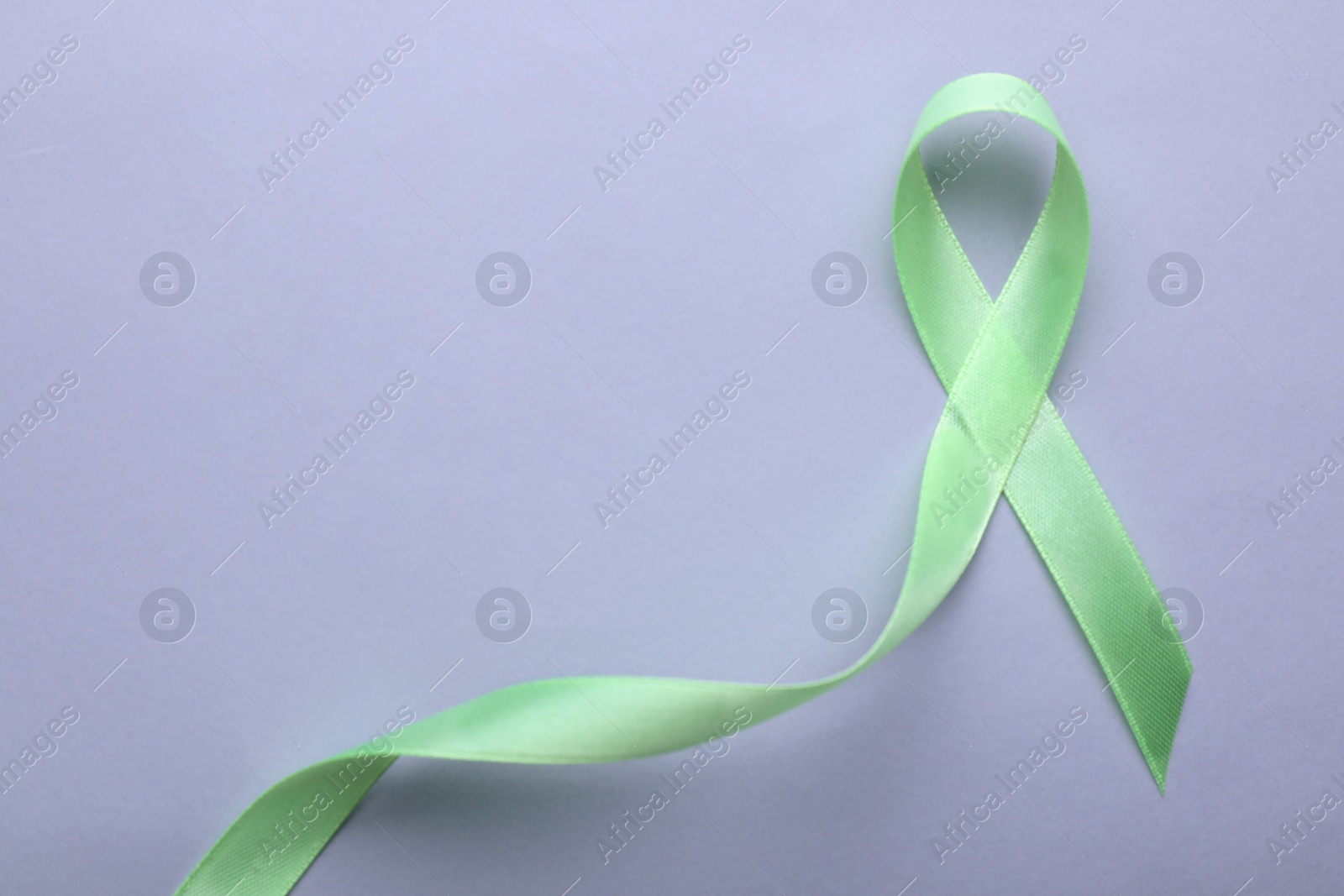 Photo of World Mental Health Day. Green ribbon on color background, top view with space for text