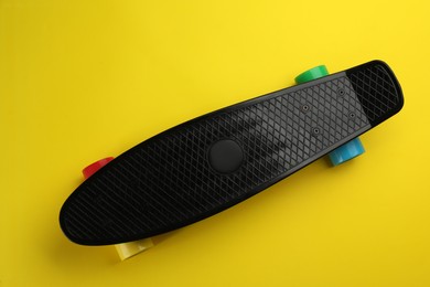 Photo of Black skateboard on yellow background, top view