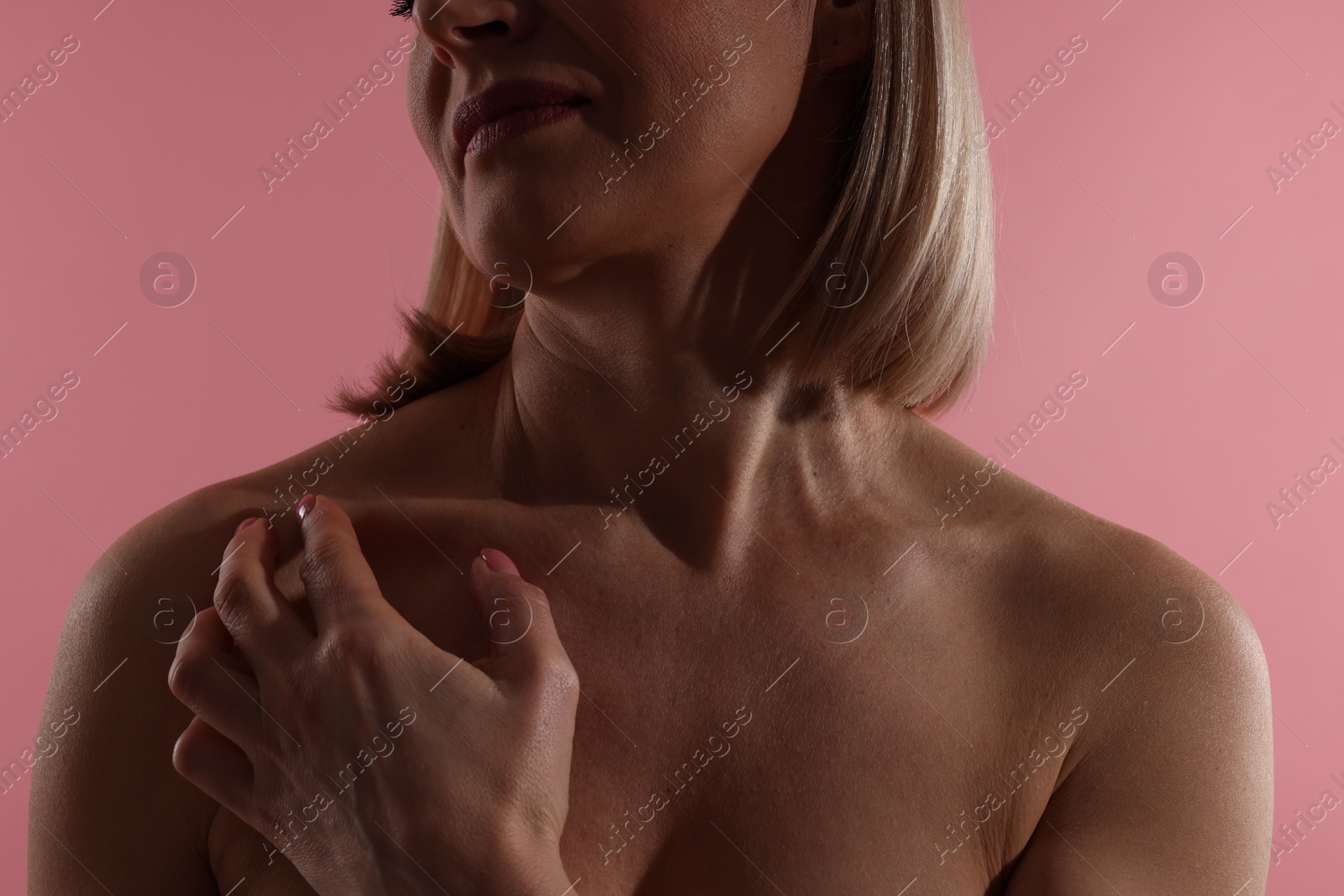 Photo of Woman touching her neck on pink background, closeup