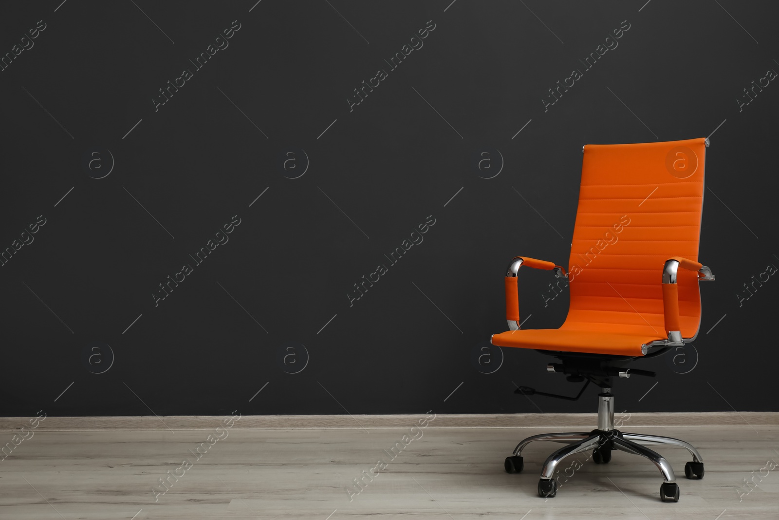 Photo of Comfortable office chair near black wall indoors. Space for text