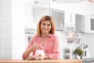Woman with piggy bank and money at home