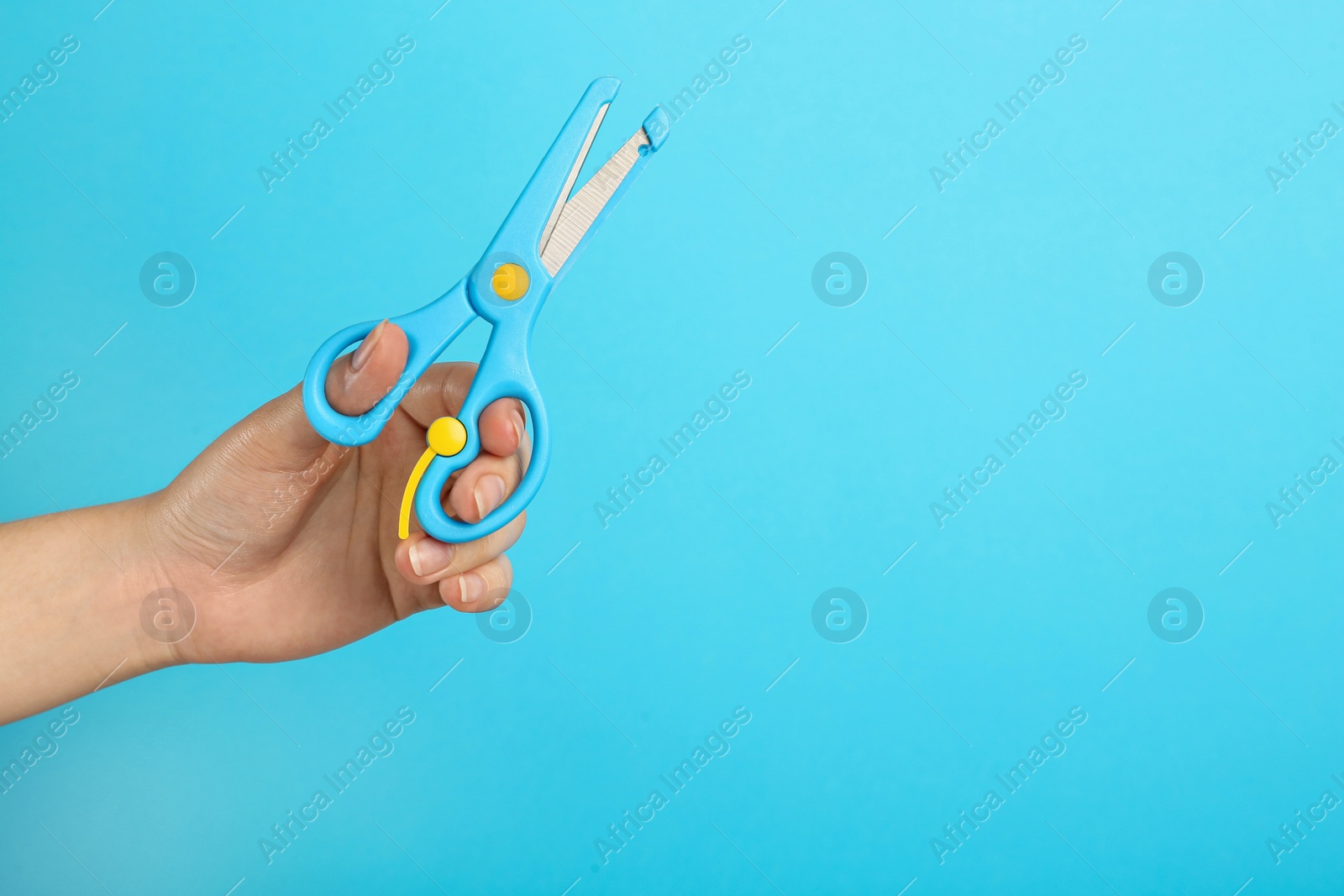 Photo of Woman holding small scissors on turquoise background, closeup. Space for text