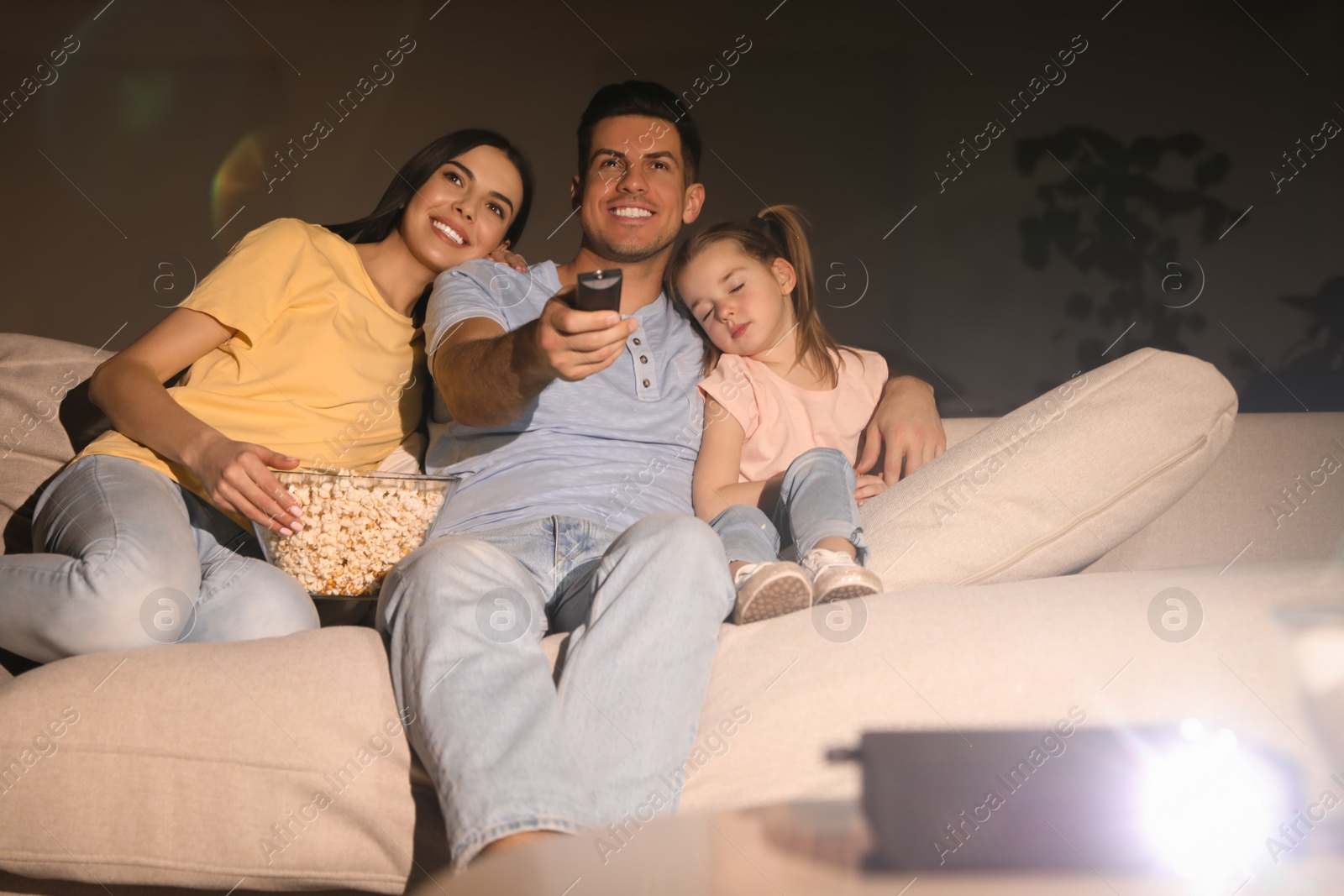 Photo of Family watching movie with popcorn on sofa at night