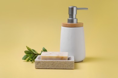 Photo of Soap bar and bottle dispenser on yellow background