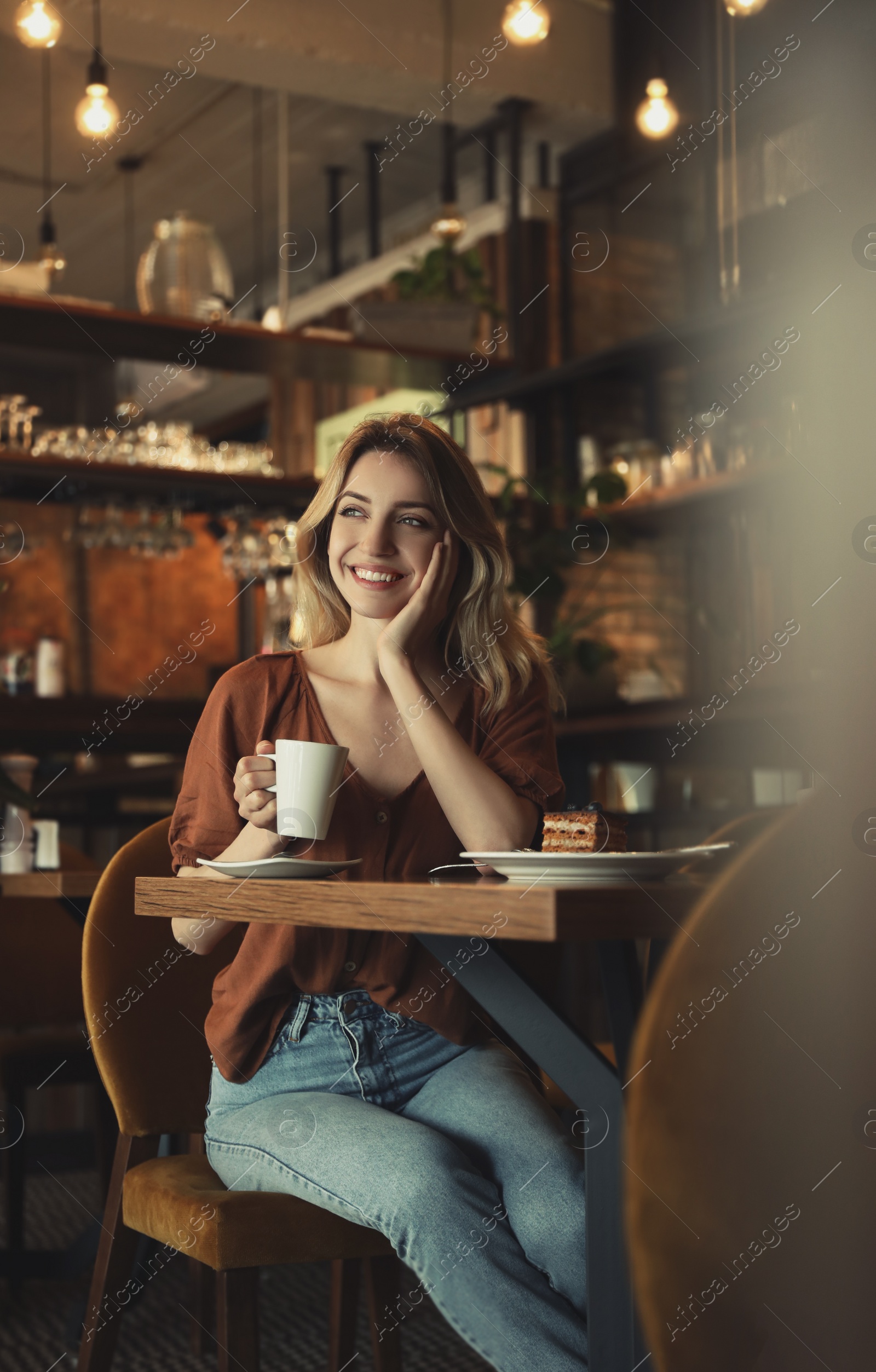 Photo of Young woman with cup of coffee at cafe in morning