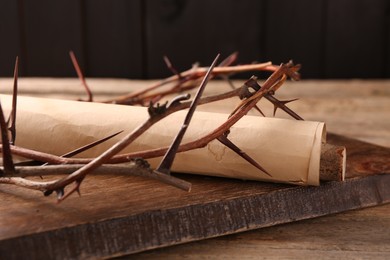 Photo of Crownthorns and old scroll on wooden table, closeup