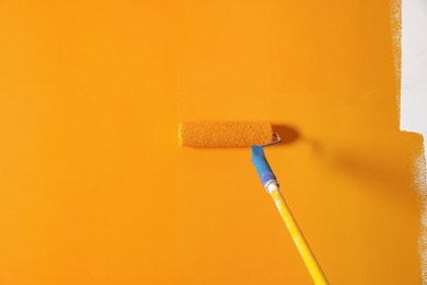 Painting wall with roller and orange dye