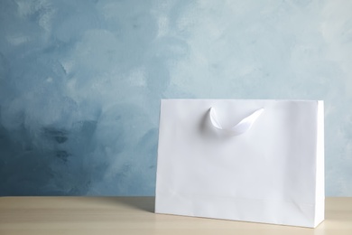 Photo of Paper shopping bag on table against color background. Mock up for design