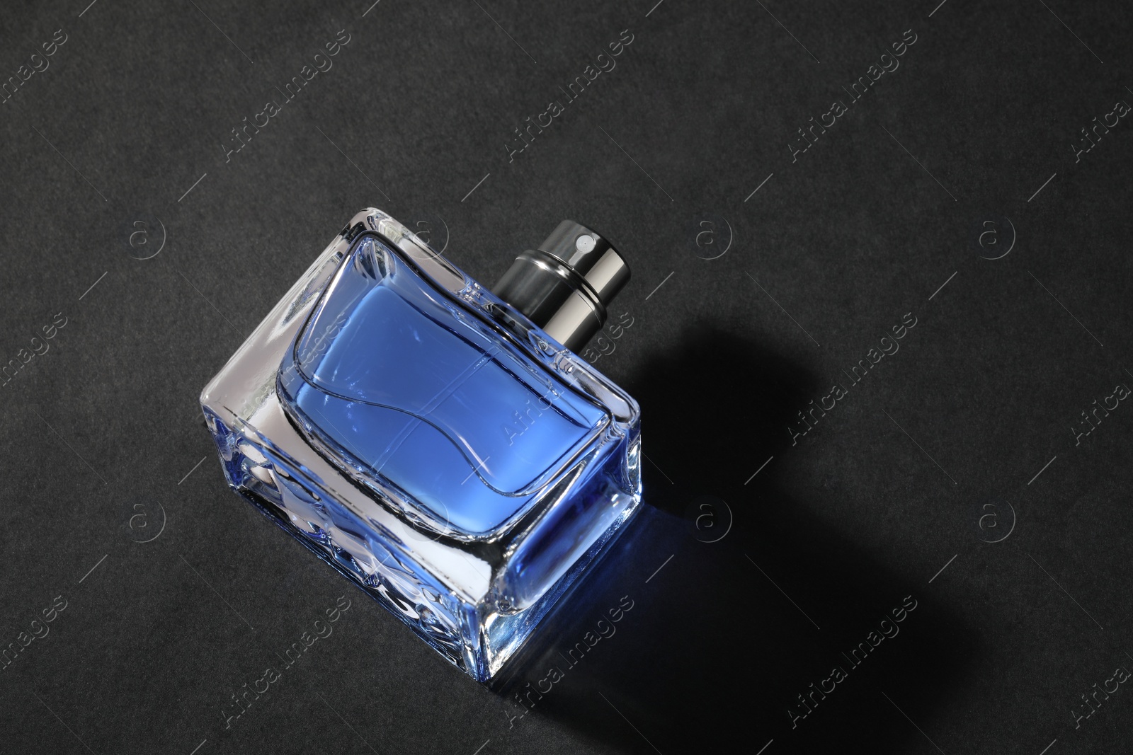 Photo of Blue men's perfume in bottle on black background, above view. Space for text