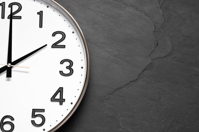 Photo of Stylish round clock on black table, top view with space for text. Interior element