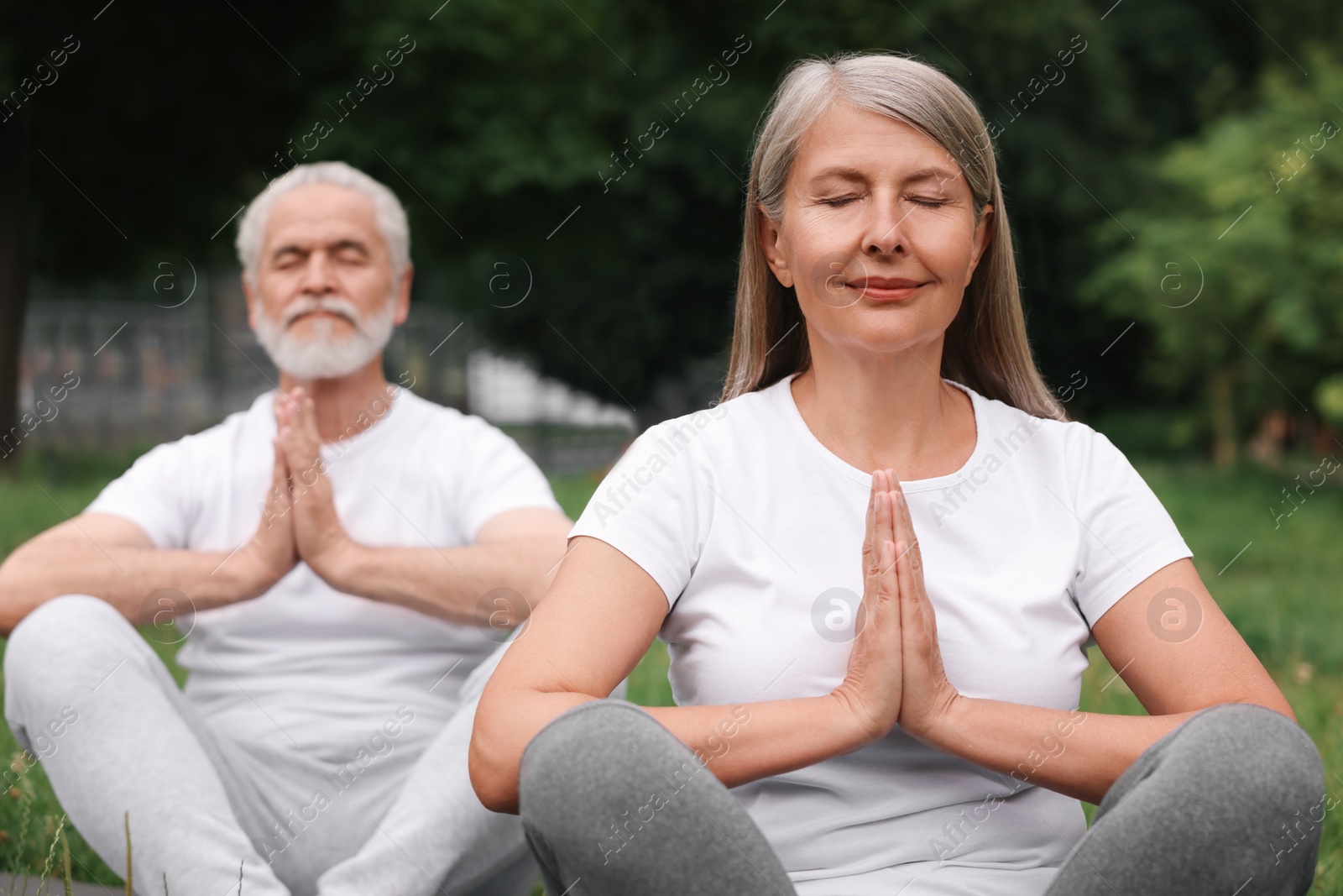 Photo of Senior couple practicing yoga in park, selective focus