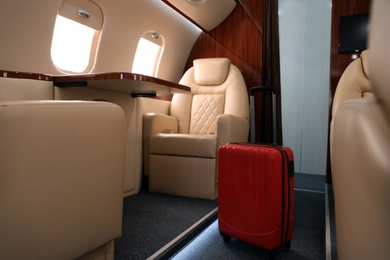 Image of Airplane cabin with red suitcase. Air travel