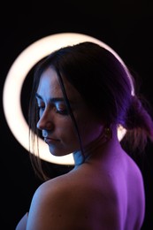 Photo of Beautiful woman and ring lamp on dark background in neon lights