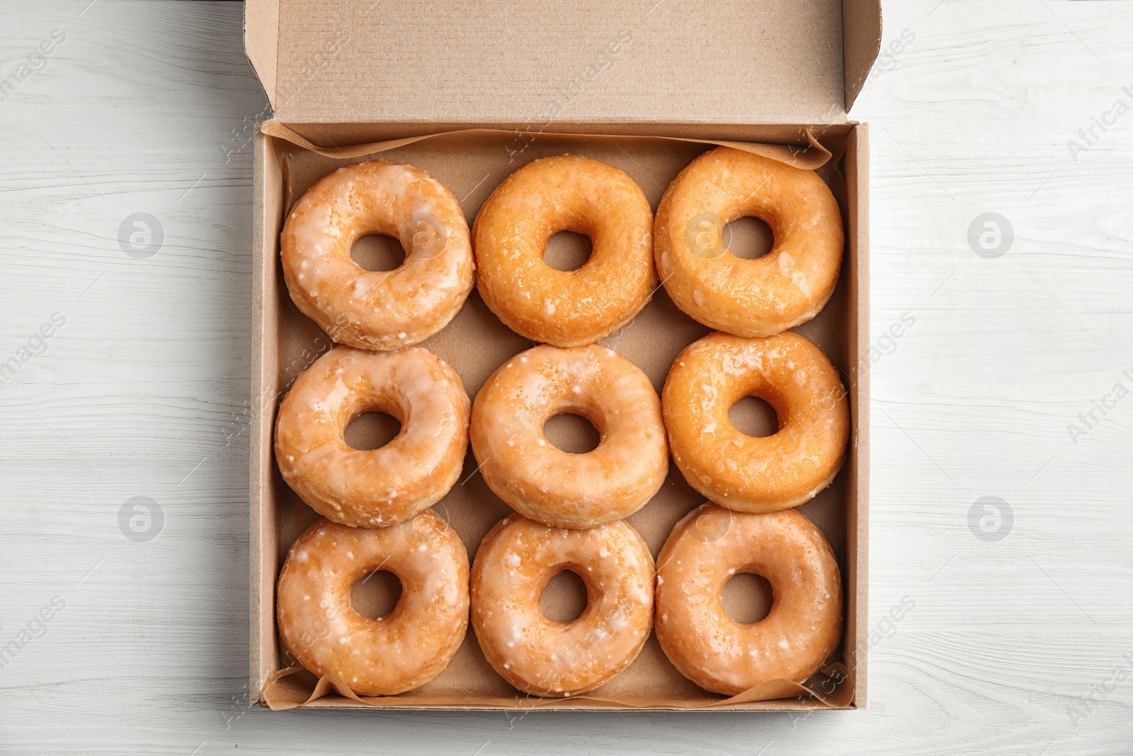 Photo of Delicious donuts on white wooden table, top view