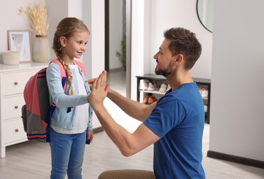 Photo of Happy father giving high five to his daughter at home. Preparing to school