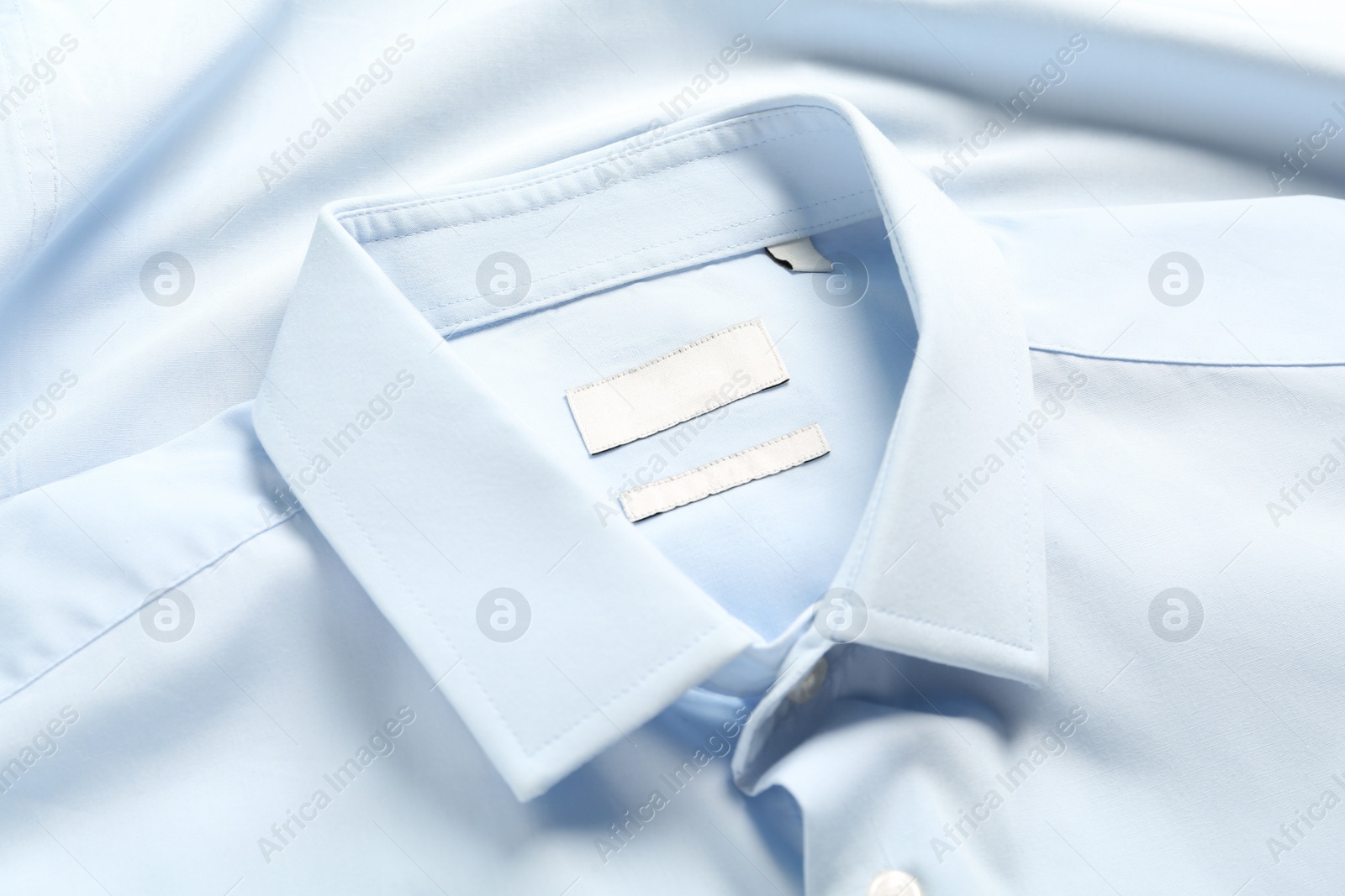 Photo of Blank clothing labels on light blue shirt, closeup