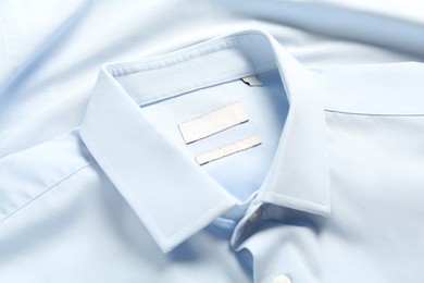 Photo of Blank clothing labels on light blue shirt, closeup