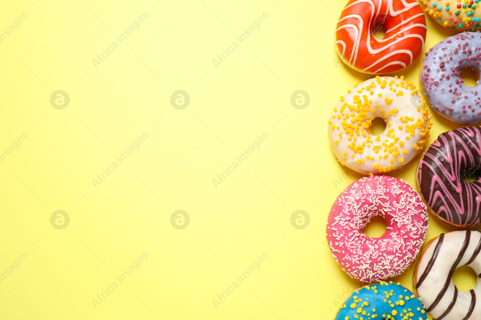 Photo of Delicious glazed donuts on yellow background, flat lay. Space for text