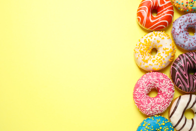 Photo of Delicious glazed donuts on yellow background, flat lay. Space for text