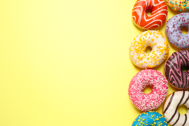 Delicious glazed donuts on yellow background, flat lay. Space for text