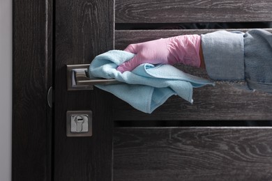 Photo of Woman wiping door handle with rag indoors, closeup