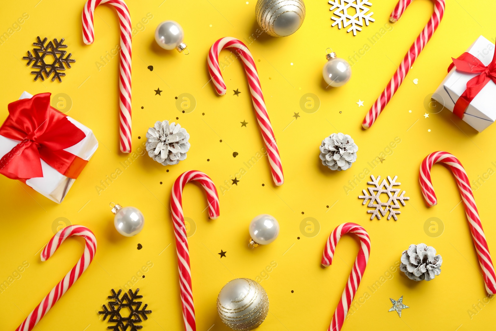 Photo of Flat lay composition with candy canes and Christmas decor on yellow background