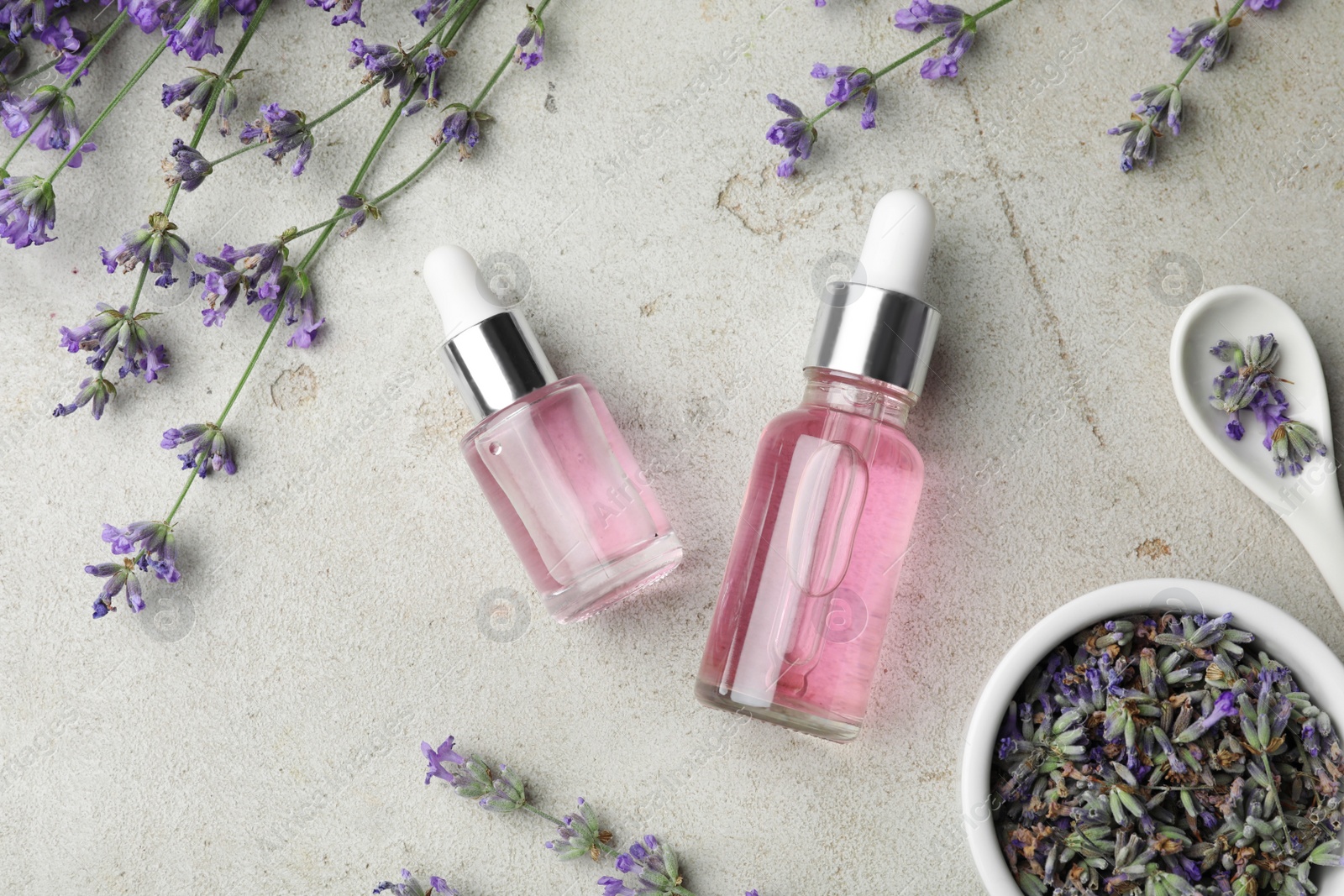 Photo of Flat lay composition with bottles of natural lavender essential oil on light stone background