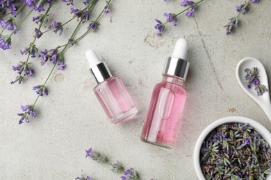 Flat lay composition with bottles of natural lavender essential oil on light stone background