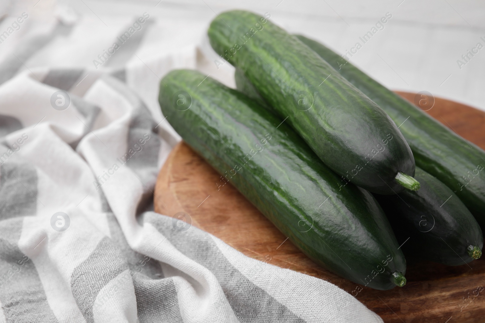 Photo of Fresh cucumbers and cloth on table, closeup