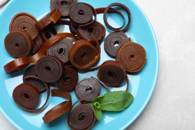 Photo of Delicious fruit leather rolls on light table, top view