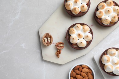 Photo of Delicious salted caramel meringue tarts and nuts on light grey marble table, flat lay